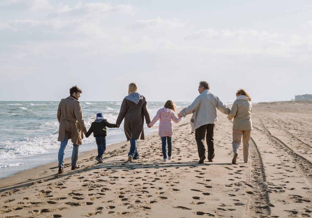 Family of six walking on the beach on a mostly sunny day